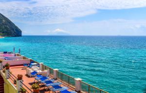 a deck with blue chairs and the ocean at Hotel Regina del Mare in Ischia