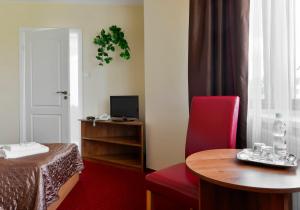 a hotel room with a table and a red chair at Harmonia in Biała Podlaska