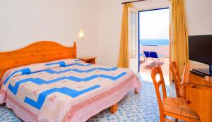 a bedroom with a bed and a television and a balcony at Hotel Regina del Mare in Ischia