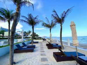 a row of benches on the beach with palm trees at Aria Vũng Tàu Resort - Căn hộ & Villa in Vung Tau
