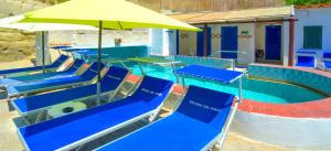 a pool with blue tables and a yellow umbrella at Hotel Regina del Mare in Ischia