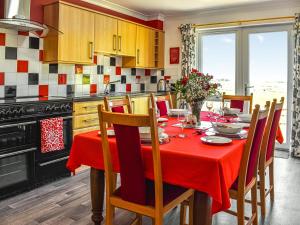 cocina con mesa y mantel rojo en Little Glengyre Farm, en Kirkcolm