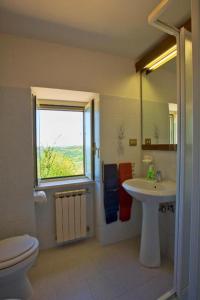 Un baño con lavabo, inodoro y ventana. en Casaletto, en Casaprota