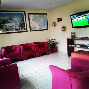 a waiting room with red chairs and a flat screen tv at Hotel Sarandi in Foz do Iguaçu +29 photos