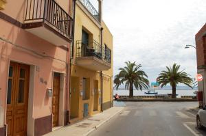 an empty street with palm trees and the ocean at Domo LA VELA in SantʼAntìoco