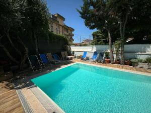 a swimming pool with blue chairs and a building at Hotel Nuovo Savi in Montecatini Terme