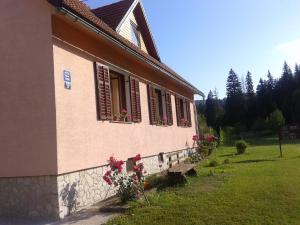 a building with flowers and a bench in front of it at Guest House Mila in Plitvička Jezera