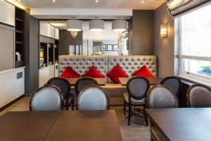 a restaurant with tables and chairs and red pillows at Best Western Buckingham Palace Rd in London