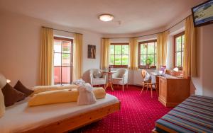 a bedroom with two beds and a desk and a table at Hotel Reitlwirt in Brixen im Thale