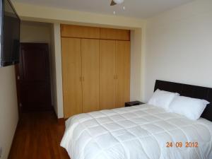 a bedroom with a large white bed and wooden cabinets at Hotel El Farolito in Lima