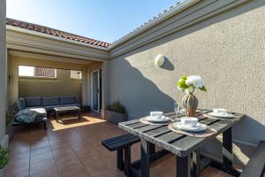 a patio with a table with cups and flowers on it at 2 Bedroom, Mountain View Penthouse, Century City in Cape Town