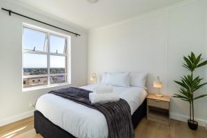 a white bedroom with a large bed and a window at 2 Bedroom, Mountain View Penthouse, Century City in Cape Town