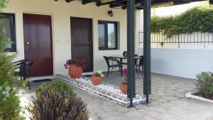 a porch with a table and chairs and potted plants at Dasea Houses in Ormos Panagias
