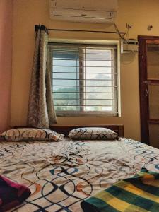Un dormitorio con una cama grande y una ventana. en Poornima home stay, en Tiruvannāmalai
