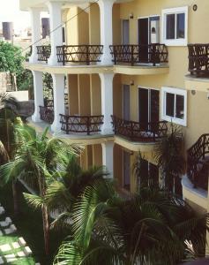 a building with balconies and palm trees in front of it at Las Palmas Condominio in Playa del Carmen