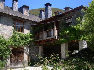 an old house with a balcony on the side of it at El Rincón del Cuco in Tejedo de Ancares