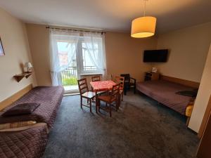 a room with a table and a bed and a window at Willa Helios in Władysławowo
