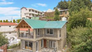 une maison avec un toit vert dessus dans l'établissement SaffronStays The Mountain Escape, à Mukteswar