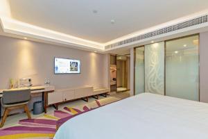une chambre d'hôtel avec un lit, un bureau et une télévision dans l'établissement Lavande Hotel Guangzhou Jingxi Southern Hospital Metro Station, à Canton