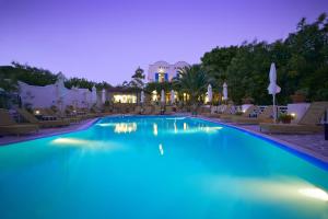 a swimming pool at night with chairs and umbrellas at Hotel Matina in Kamari