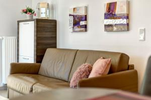 ein Wohnzimmer mit einer braunen Couch mit zwei rosa Kissen in der Unterkunft Residenz am Balmer See - BS 37H mit Wellnessbereich in Balm