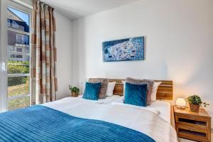ein Schlafzimmer mit einem Bett mit blauen Kissen und einem Fenster in der Unterkunft Residenz am Balmer See - BS 37H mit Wellnessbereich in Balm + 14 Fotos