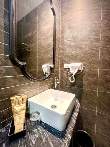 a bathroom with a white sink and a mirror at Mia Garden Hotel in Dinh Ðiền Buôn Hô