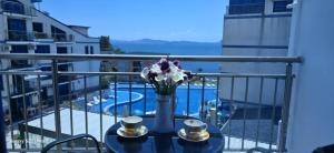 a table with two cups and a vase with flowers on a balcony at Divine place Pomorie in Pomorie
