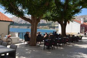 a group of people sitting at tables under trees at Apartment Željko in Baška