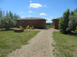 a dirt road leading to a cabin with yellow picnic tables at Orchard View Bed and Breakfast in Moose Jaw