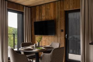 a dining room with a table and chairs and a television at WIDOQ Resort Szczyrk Domki in Szczyrk
