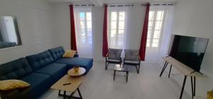 a living room with a blue couch and a flat screen tv at Le Central in Villeneuve-sur-Yonne