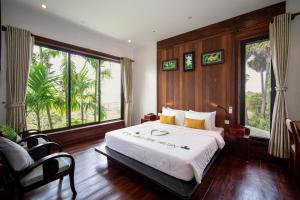 a bedroom with a large bed and large windows at Domnak Pichet in Siem Reap