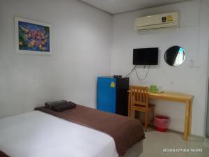 a bedroom with a bed and a desk and a refrigerator at เพชรรัตน์รีสอร์ทแอนด์สปา in Surat Thani