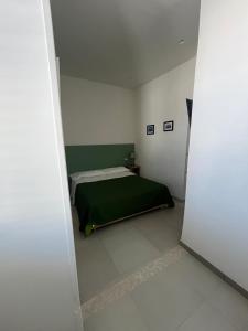 トッレ・アンヌンツィアータにあるVictoria Apartmentsの白い部屋に緑のベッドが備わるベッドルーム1室