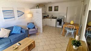 a living room with a blue couch and a kitchen at 85 on First - Sawtell Apartments in Sawtell