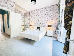 - une chambre avec un lit blanc et du papier peint floral rose dans l'établissement City Centre Escape with Private Garden, à Édimbourg