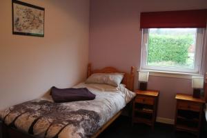 a small bedroom with a bed and a window at The Old School in Dallavich