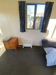a room with a bed and a table and a window at Waitomo Farmstay - Fantail Cabin 6 in Waitomo Caves