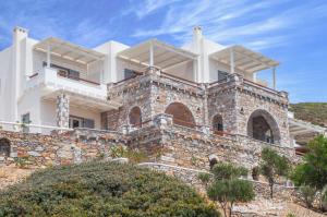 a large white house on top of a stone wall at Skopelitis Village in Katapola