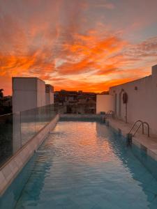 a pool on the roof of a building with a sunset at Hotel Palacio De Úbeda 5 G.L in Úbeda