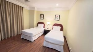 two beds in a hotel room with white sheets at القصر العالي للوحدات السكنية المفروشة in Al Khobar
