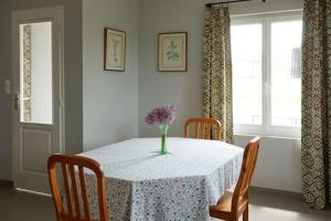 a dining room table with a vase of flowers on it at La Maison de la Mare in Doudeville