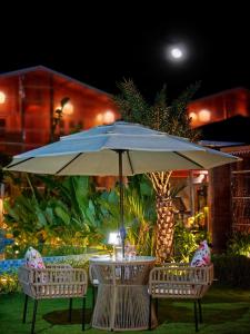 a table with a blue umbrella and two chairs at The Clouds Resort Arambol, Goa in Arambol +217 photos