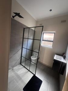 a bathroom with a shower and a toilet and a window at Imbarudo Residence in Victoria Falls