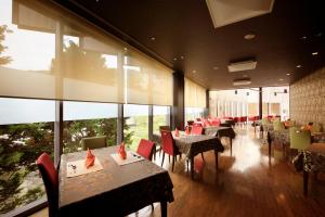 a restaurant with tables and chairs and large windows at Atami Tensui in Atami