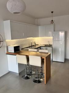 eine Küche mit weißen Schränken und einer Theke mit Stühlen in der Unterkunft Sokrates in Larnaka
