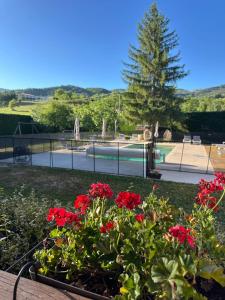 a garden with red flowers and a swimming pool at L'Hôtentique in Turriers