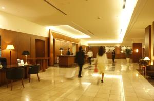 a couple of people walking through a lobby at Royal Pines Hotel Urawa in Saitama