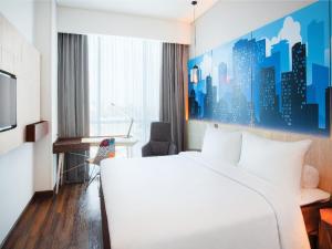 a hotel room with a white bed and a desk at The Southern Hotel Surabaya in Surabaya +11 photos